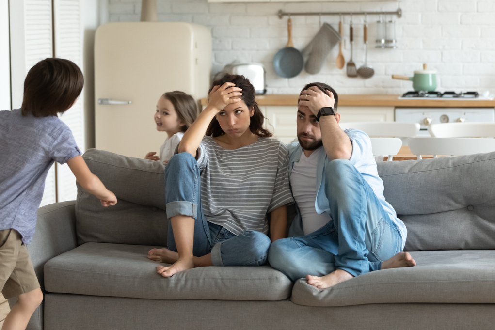 Stressed young parents tired of crazy loud children.